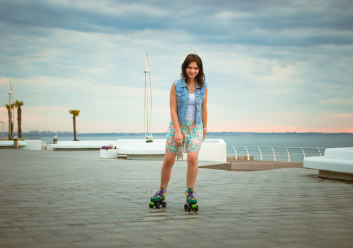 Young woman roller skating near the sea on roller squads