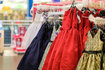 Girl dresses in different colours on hangers in kids store