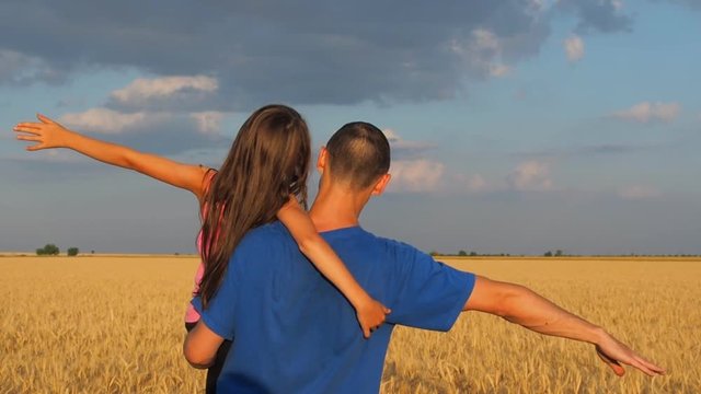 Dad and daughter are playing a plane. Dad and daughter on the wheat field.