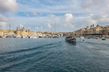 Fototapeta premium A Luzzu, a traditional maltese fishing boat sailing in Vittoriosa Yacht Marina, Valletta, Malta