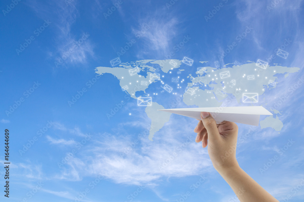 Poster hand with paper plane against blue sky with sending message with email on world map, network communi