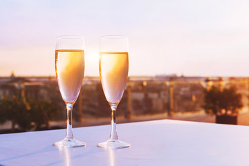 two glasses of champagne at rooftop restaurant with view of city skyline, luxury romantic dinner for couple