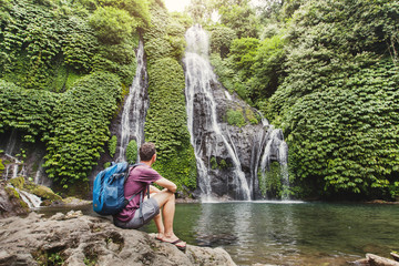 tourist backpacker looking at waterfall in Bali