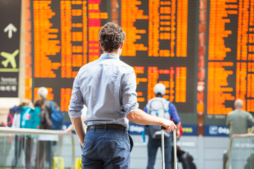 delay of flight, people passengers waiting in airport and looking at electronic timetable