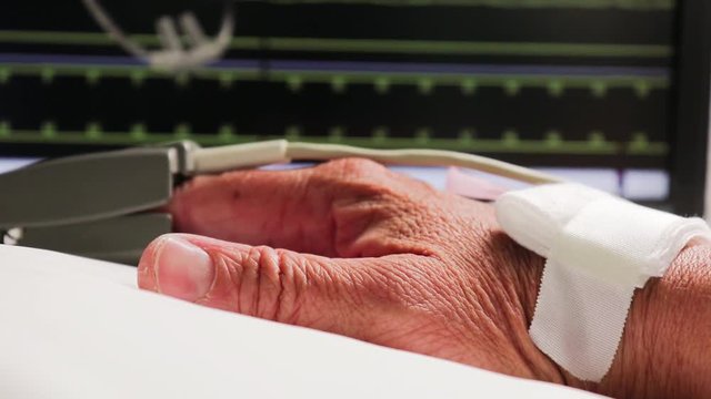 Une personne ag&eacute;e branc&eacute;e &agrave; l'appareil de surveillance.