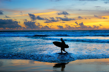 Surfer with surfboard at sunset