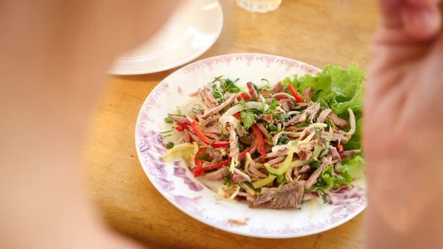Someone eats meat salad with a fork and a knife. close-up. Slow motion.