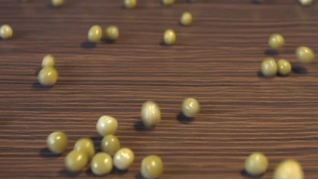 Canned green peas on a brown wooden background. 2 Shots. Slow motion. Horizontal pan. Close-up.