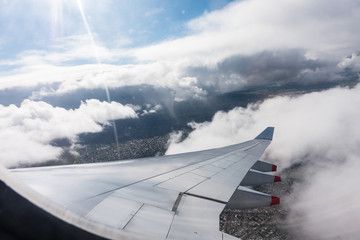 Fototapeta na wymiar Airplane window view showing wing of plane flying over clouds