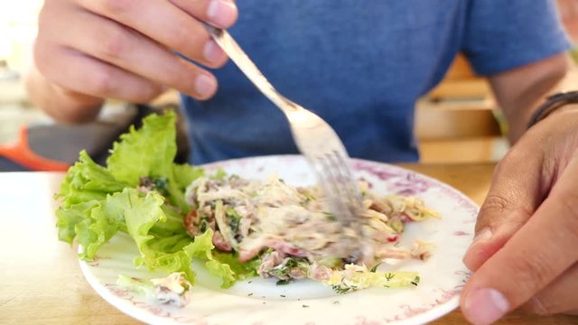 Someone eats meat salad with a fork and a knife. close-up. Slow motion.