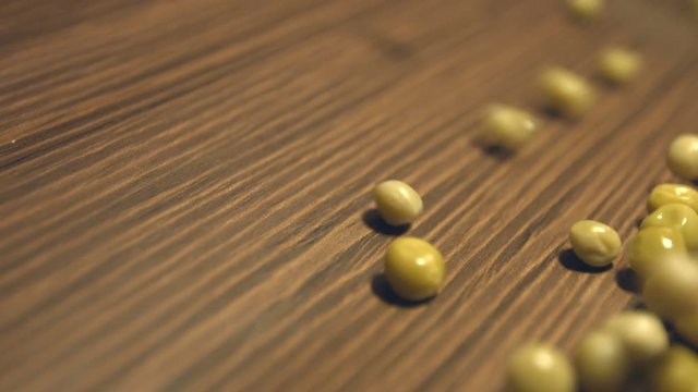 Canned green peas on a brown wooden background. 2 Shots. Vertical pan. Close-up.
Canned green peas are rolling down ( from left to right ) on a brown wooden background and fills the all space frame.
