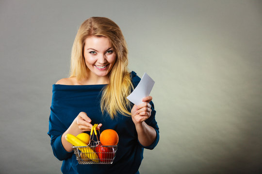 Happy woman holding shopping basket with fruits