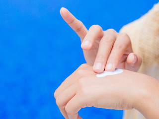 Woman hand apply sunscreen / sunblock by the swimming pool. Vacation and relaxation, summer travel concept.