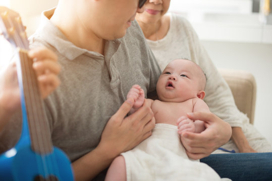 Asian Grandparent Playing Music With Father And Baby Indoor