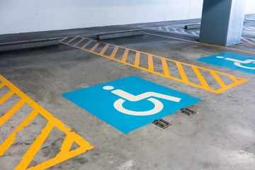 Handicap sign and yellow stripes on cement floor at parking area