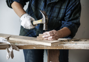 Woman carpenter using hammer pushing nail on a wood