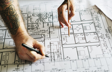 Hands with tattoo working on a blueprint