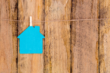 Blue color wooden house shape hanging on string against rustic wooden background - sign