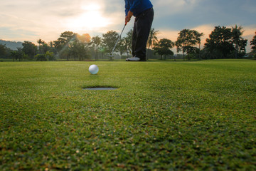 Golf ball putting by player on the green runs to the hole
