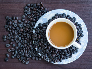 Coffee in cup with coffee beans around.