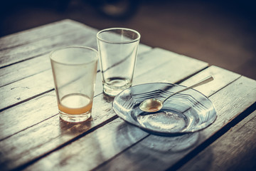 Empty glass of hot tea in with saucer and spoon on wooden table vintage tone, shallow focus.