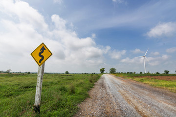 Dirt road with signpost and wind turbine to generate electricity with white clouds and blue sky beautiful. renewable energy source.