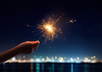 Female hand holding a burning sparkler - Powered by Adobe