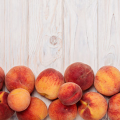 Ripe tasty peaches on a light wooden background.