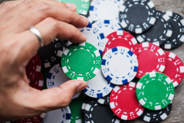 Naklejka premium Close-up hand holding casino gambling chip, selective focus shallow depth of field