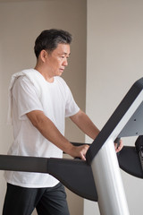 old senior man walking, running, exercising, working out in gym with threadmill machine