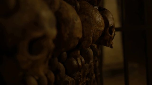 Rack focus shot of human skulls in an underground ossuary. Halloween / horror / nightmare. 4K rack focus shot.
