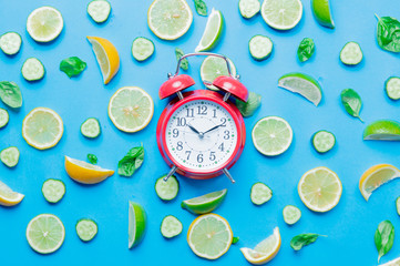 cutted lemons and limes and alarm clock