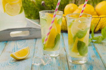 lemonade with mint on rocks served in a glass with a straw