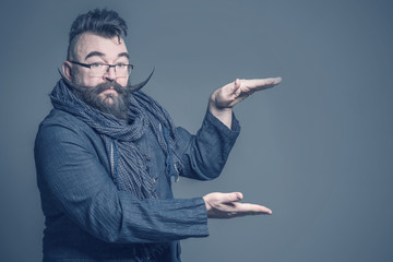 Adult bearded man with a very long mustache holding his hand over his hand