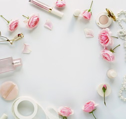 Flat lay, top view feminine desk, workspace , female make up accessories and bouquet roses.Beauty blog concept.Copy space