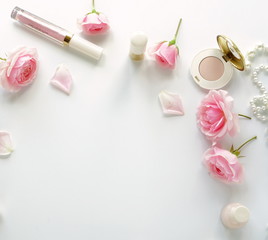 Flat lay, top view feminine desk, workspace , female make up accessories and bouquet roses.Beauty blog concept.Copy space