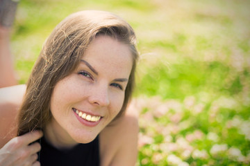 Portrait of a young beautiful woman with long hair against a background of green leaves