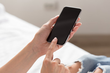 Woman checking the cell phone on the bed
