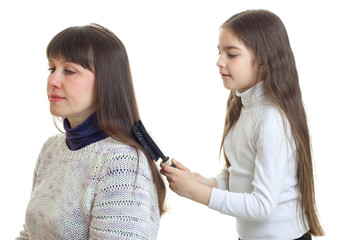 little young girl makes a hairstyle to her mother