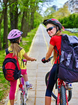 Bicycle path and sign with children. Girls wearing bicycle helmet with rucksack ciclyng ride. Kids are on yellow bike lane. Alternative to urban transport for participate in fun cycling competitions.
