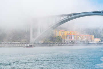 Fototapeta na wymiar Porto in Portugal, view of the Douro river in the mist, with a traditional boat 