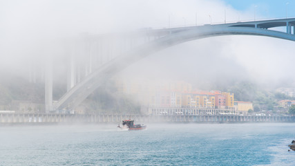 Porto in Portugal, view of the Douro river in the mist, with a traditional boat  