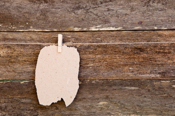 Torn homemade Paper - cardboard label hanging on clothespin against old wooden background