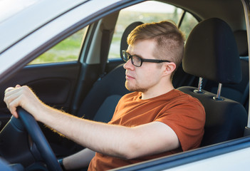 Handsome young man in a brown T-shirt driving a car