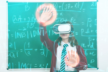 Schoolgirl with virtual reality glasses in classroom