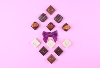 Various chocolate pralines on pink trendy background.