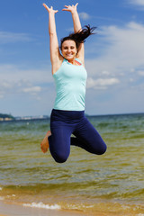 młoda atrakcyjna dziewczyna skacze z radości na plaży 