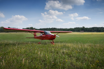 Fototapeta na wymiar Light aircraft. Light red school airplane on airport grass