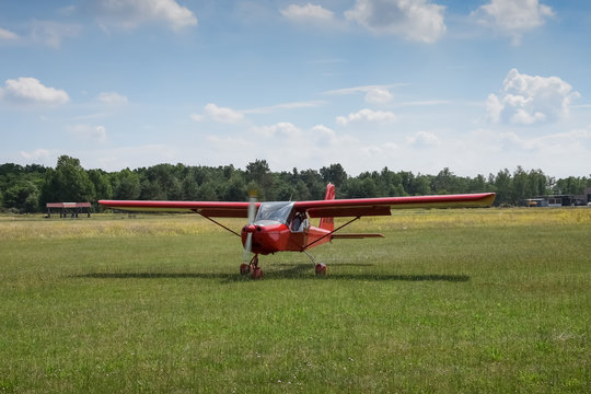 Light aircraft. Light red school airplane on airport grass after landing. The propeller rotates