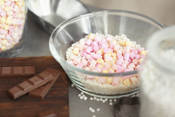 Glass bowl with crispy rice balls, marshmallow and chocolate bars on table